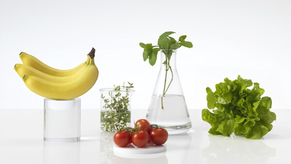 Fresh Fruit and Vegetables on a White Countertop in Glass Beakers