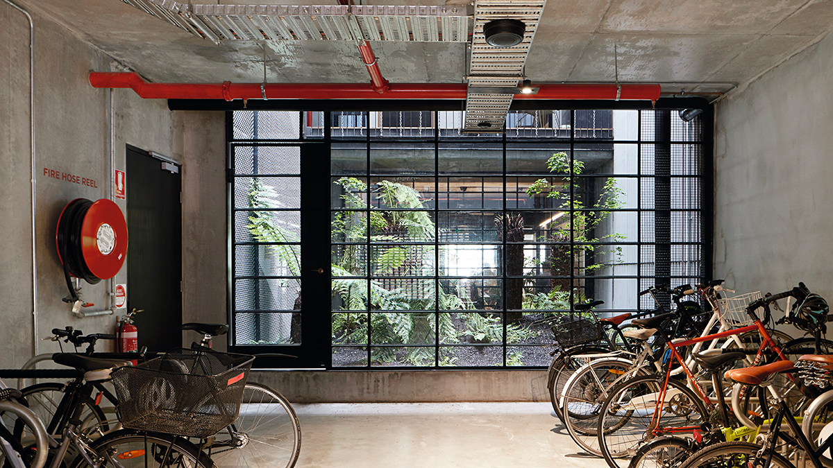 Concrete industrial style garage with black grid of windows and filled with bicycles.
